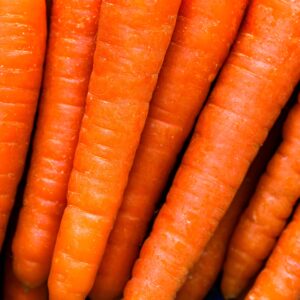 Fresh organic carrots closely stacked together, showcasing vibrant orange hues and healthy textures.