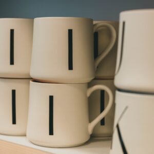 Close-up of stacked white alphabet mugs on display, perfect for modern kitchen decor.