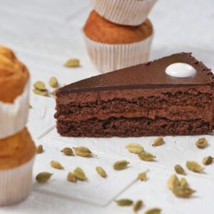 Close-up of a chocolate cake slice, cardamom, and muffins, perfect for dessert lovers.