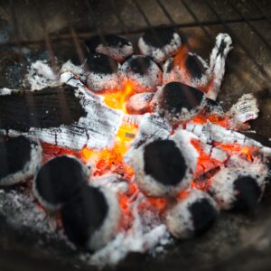 Close-up of glowing charcoal briquettes in a barbecue, ready for grilling.