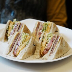 Close-up of club sandwiches with ham, cheese, and veggies on a plate.