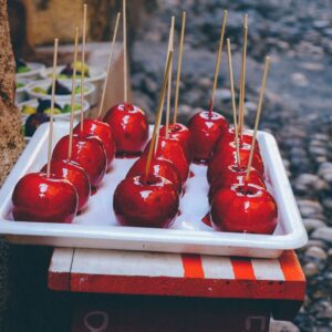 A rustic tray filled with glossy candy apples showcased outdoors on a cobbled street, inviting and sweet.