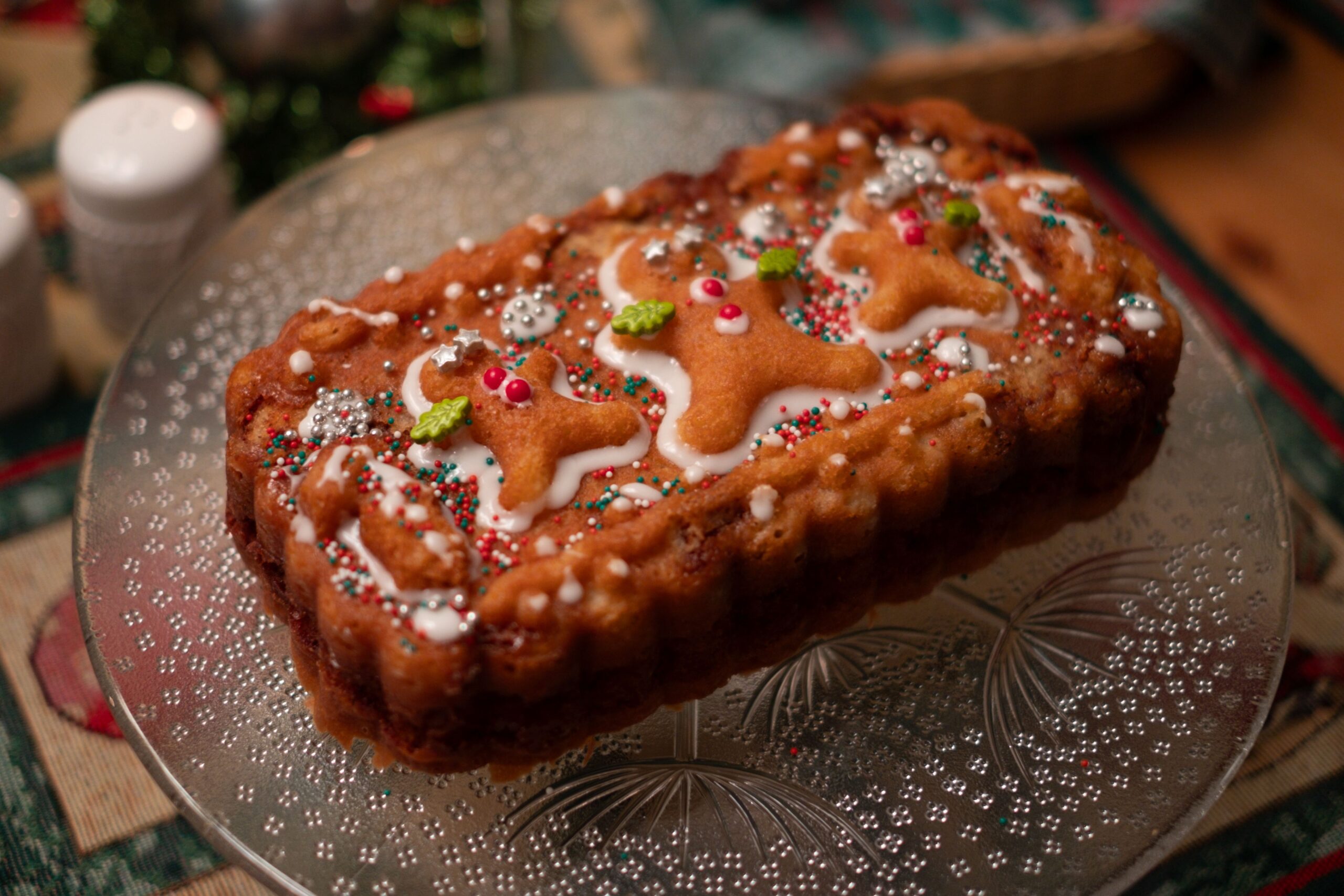 pexels photo 30913008 30913008 Delicious gingerbread cake topped with festive icing and sprinkles on a glass platter, perfect for holiday celebrations.