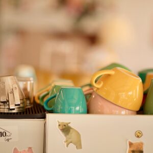 A collection of colorful coffee cups on an espresso machine in a cozy cafe setting.