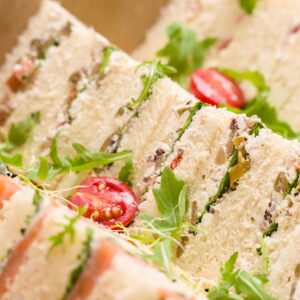 Close-up of assorted gourmet sandwiches with fresh arugula and tomatoes, perfect for catered events.