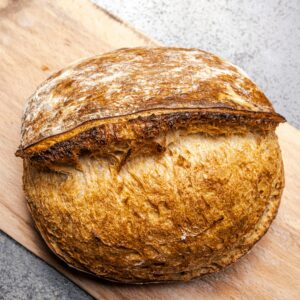 Home Fresh artisan sourdough bread with a golden crust on a wooden board.