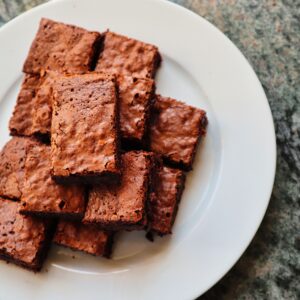 A top view of freshly baked, delicious chocolate brownies served on a white ceramic plate.