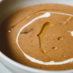 Close-up of a rich mushroom soup topped with creamy swirl and olive oil, perfect for gourmet cuisine enthusiasts.