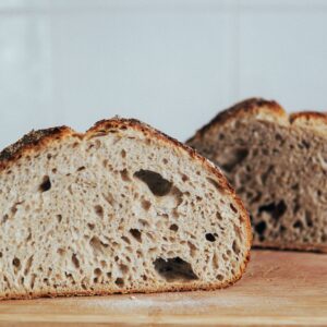 Cut slices of wheat bread loaf placed on wooden cutting board at kitchen