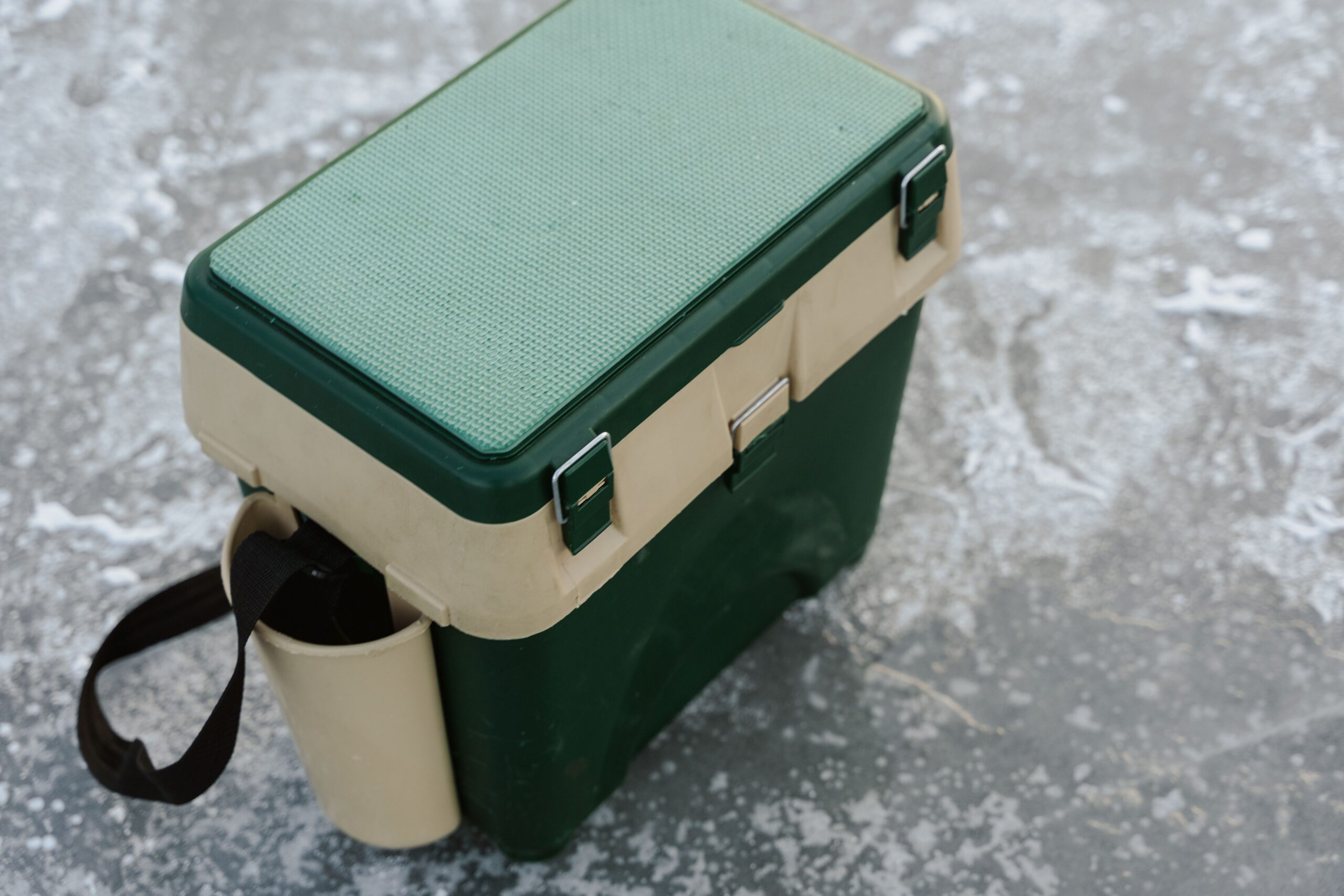 pexels photo 6831179 6831179 A green and beige cooler sits on a frozen ice surface, ideal for outdoor adventures.