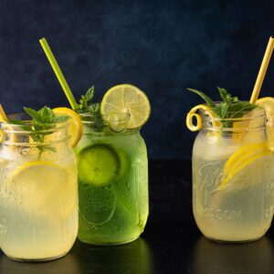 Three mason jars filled with lemon and lime refreshment garnished with mint.